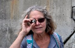 Photograph of Laura Barker looking at the camera through a sea shell